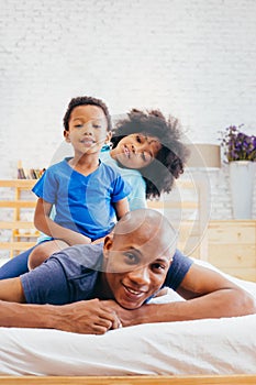 African American family of three, kids sitting on father`s back