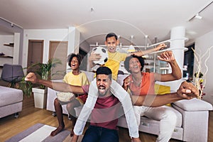 African american family watching soccer match on television in living room at home