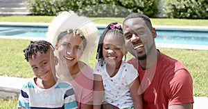 African American family with a young biracial woman smiles together outdoors at home