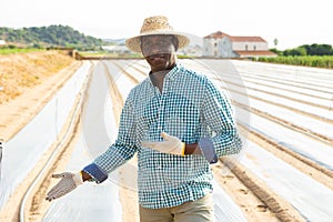 African american farmer standing in field covered with polyethylene mulch