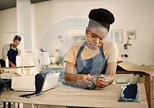 African american fashion designer cutting a piece of denim. Tailor working in her studio. Seamstress cutting a piece of