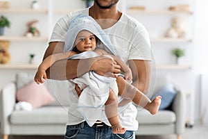 African american father carrying his infant baby in towel after bathing