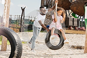 african american father and daughter on tire swing having fun photo