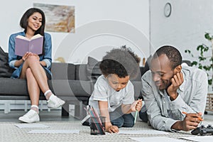 african american father drawing with son and mother reading book