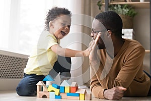 African American father with toddler son playing with wooden constructor photo