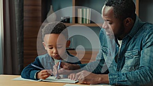 African American father help ethnic little schoolboy pupil with homework at home dad helping school child son with