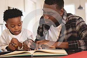 African American father helping his son with homework at table