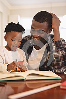 African American father helping his son with homework at table