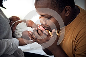 African American father kissing foot, his 12-day-old baby newborn