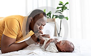 African American father kissing foot, his 12-day-old baby newborn