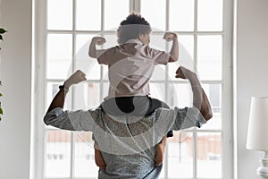 African american father with little son on shoulders showing biceps.