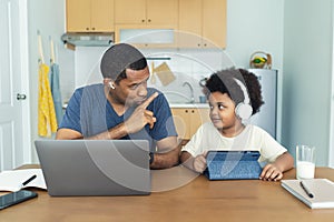 African American father silencing his son while communicating by video call via laptop computer, online meeting at home. Say hush