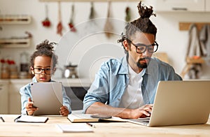 African american father and son using gadgets laptop and tablet while sitting at desk at home