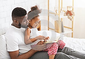 African american father teaching his little daughter how to read