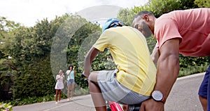 African american father teaching son to ride bicycle, mother and sister clapping, slow motion