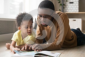 African American father and toddler son reading book together photo