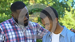 African-american father trying to comfort unhappy son, family support, trust