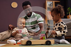 African American father with two children building with wooden blocks together