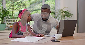 African american father using laptop and helping his daughter with homework at home