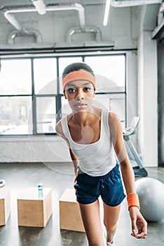 african american female athlete in headband and wristbands exercising