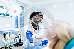 African american female dentist treating patient at clinic. Dental clinic concept.