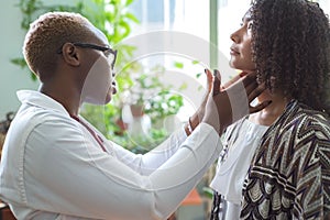 An African American female doctor examines with her fingers, palpates her neck and lymph nodes. Pain in the neck. Mixed race