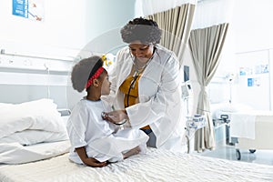 African american female doctor examining girl patient using stethoscope at hospital