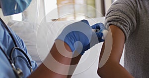 African american female doctor wearing face mask vaccinating african american patient