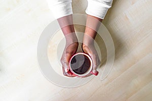 African American Female hands holding red cup of coffee espresso or cappuccino on on granite Kitchen counter-top. Black woman hand