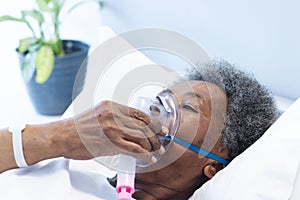 African american female senior patient wearing oxygen mask in hospital room