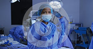 African american female surgeon wearing face mask and protective clothing in operating theatre