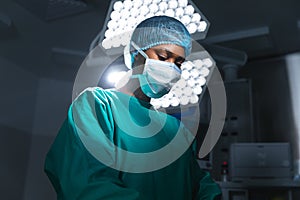African american female surgeon wearing surgical gown and face mask in operating theatre