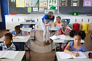 African american female teacher with digital tablet teaching a girl at elementary school