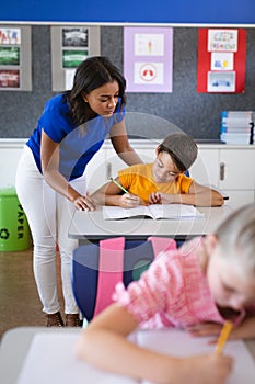 African american female teacher teaching caucasian boy in the class at elementary school