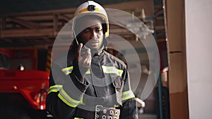 African American fireman in equipment with helmet use walkie talkie at the station