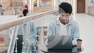 African american focused serious millennial business man male freelancer student guy user sitting at table in cafe with