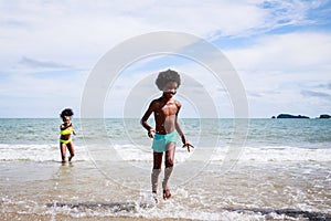 African American friendship in swimwear enjoying running to play the waves on beach. Ethnically diverse concept. Having fun after