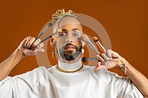 African american gay applying make up isolated on brown background