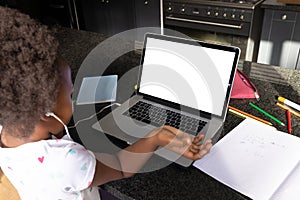 African american girl with afro hair attending online lecture over laptop on table at home