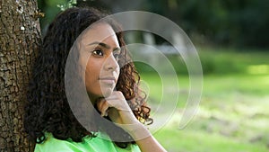 African American girl biracial teenager young woman outside sad or depressed then happy smiling sitting leaning against a tree