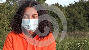 African American girl biracial teenager young woman outside wearing a face mask during COVID-19 Coronavirus pandemic