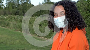 African American girl biracial teenager young woman outside wearing a face mask during COVID-19 Coronavirus pandemic