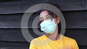 African American girl biracial teenager young woman outside wearing a face mask during COVID-19 Coronavirus pandemic