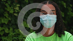 African American girl biracial teenager young woman outside wearing a face mask during COVID-19 Coronavirus pandemic