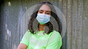 African American girl biracial teenager young woman outside wearing a face mask during COVID-19 Coronavirus pandemic
