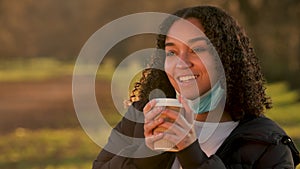 African American girl biracial teenager young woman wearing a face mask drinking coffee during COVID-19 Coronavirus pandemic