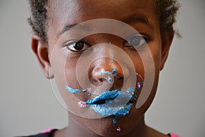 African American Girl with Bright Blue Frosting on Face