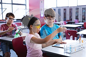 African american girl and caucasian boy holding test tube in science class at laboratory