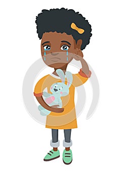 African-american girl crying and holding toy.