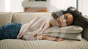 African American girl with curly hair naps turning away on sofa with closed eyes